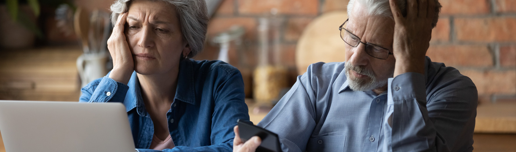 couple-sitting-at-table-looking-at-bills-on-labtop