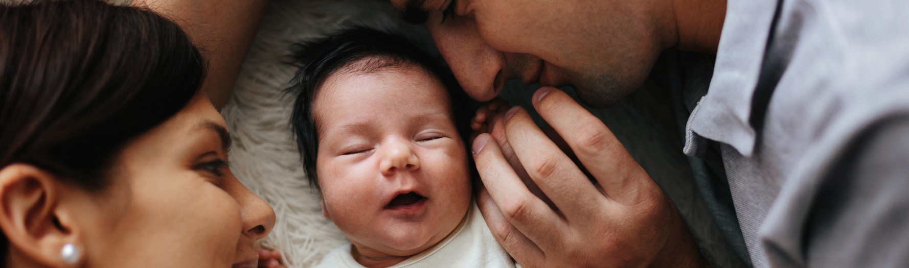 woman-man-smiling-at-new-born-sleeping